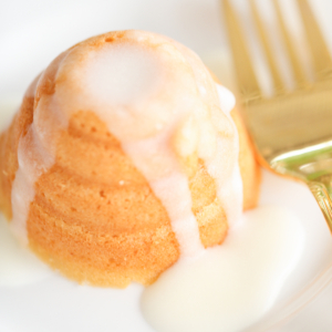 A honey lemon cake on a white plate with a gold fork.