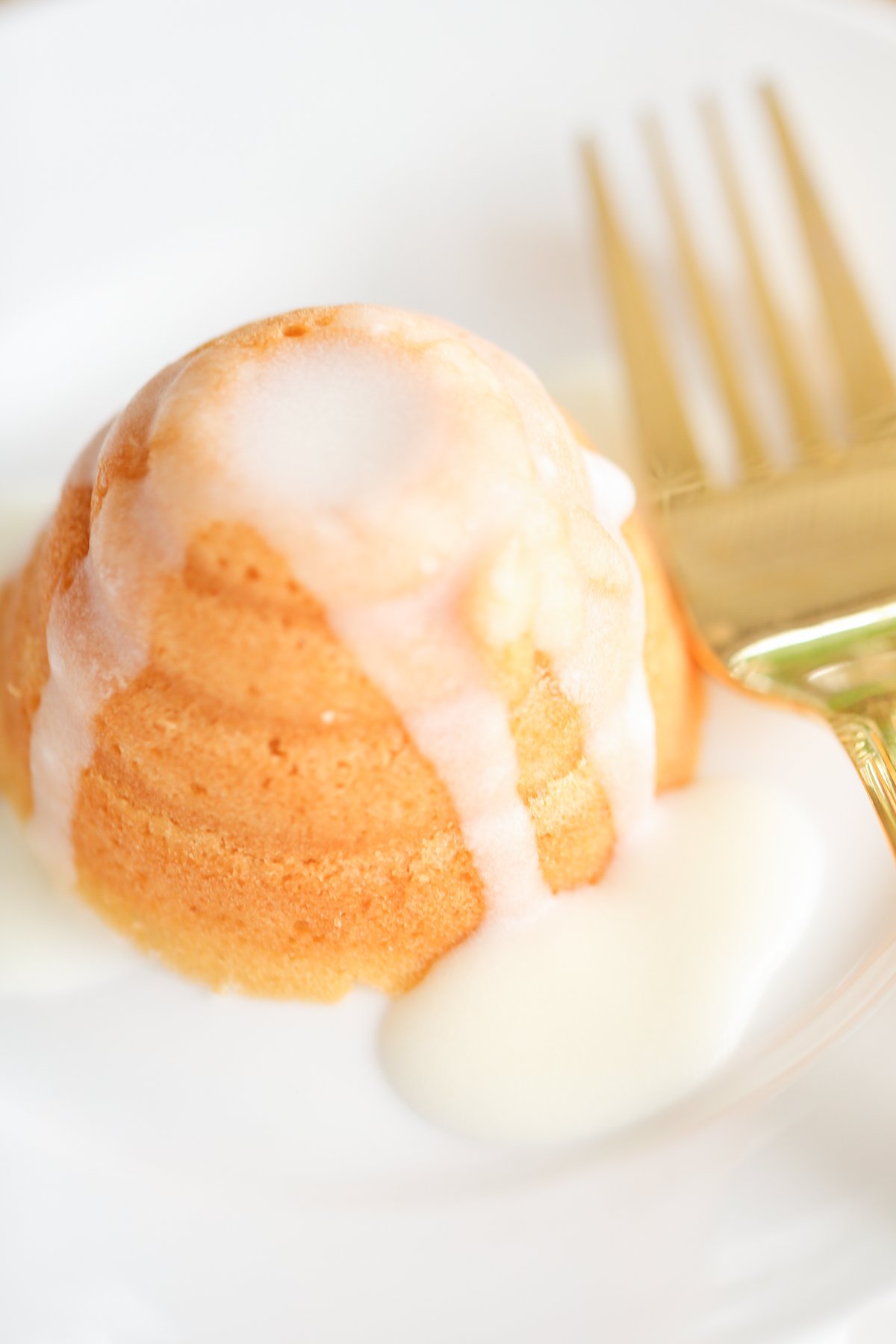 A honey lemon cake on a white plate with a gold fork.