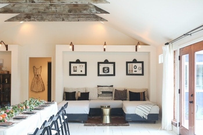 A farmhouse living room with raw wood barn inspired beams, white walls and vintage furnishings.