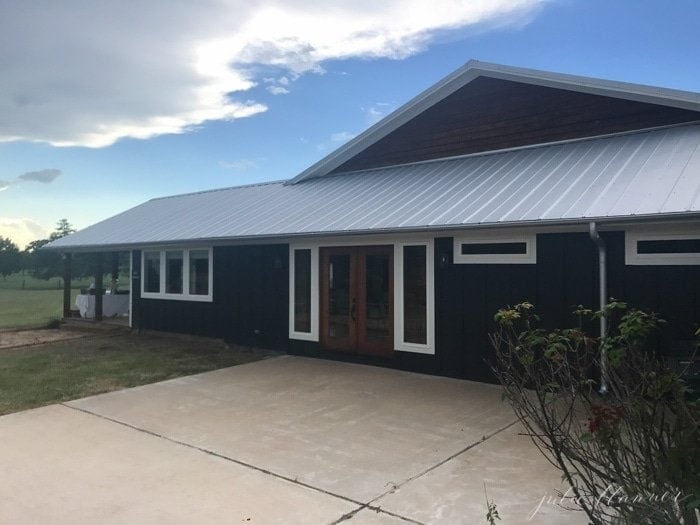 A Texas industrial farmhouse with black siding and a metal roof.