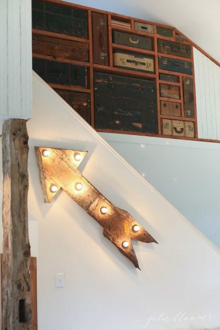 Incredible farmhouse interior design wall featuring vintage suitcases sandwiched between wooden beams.