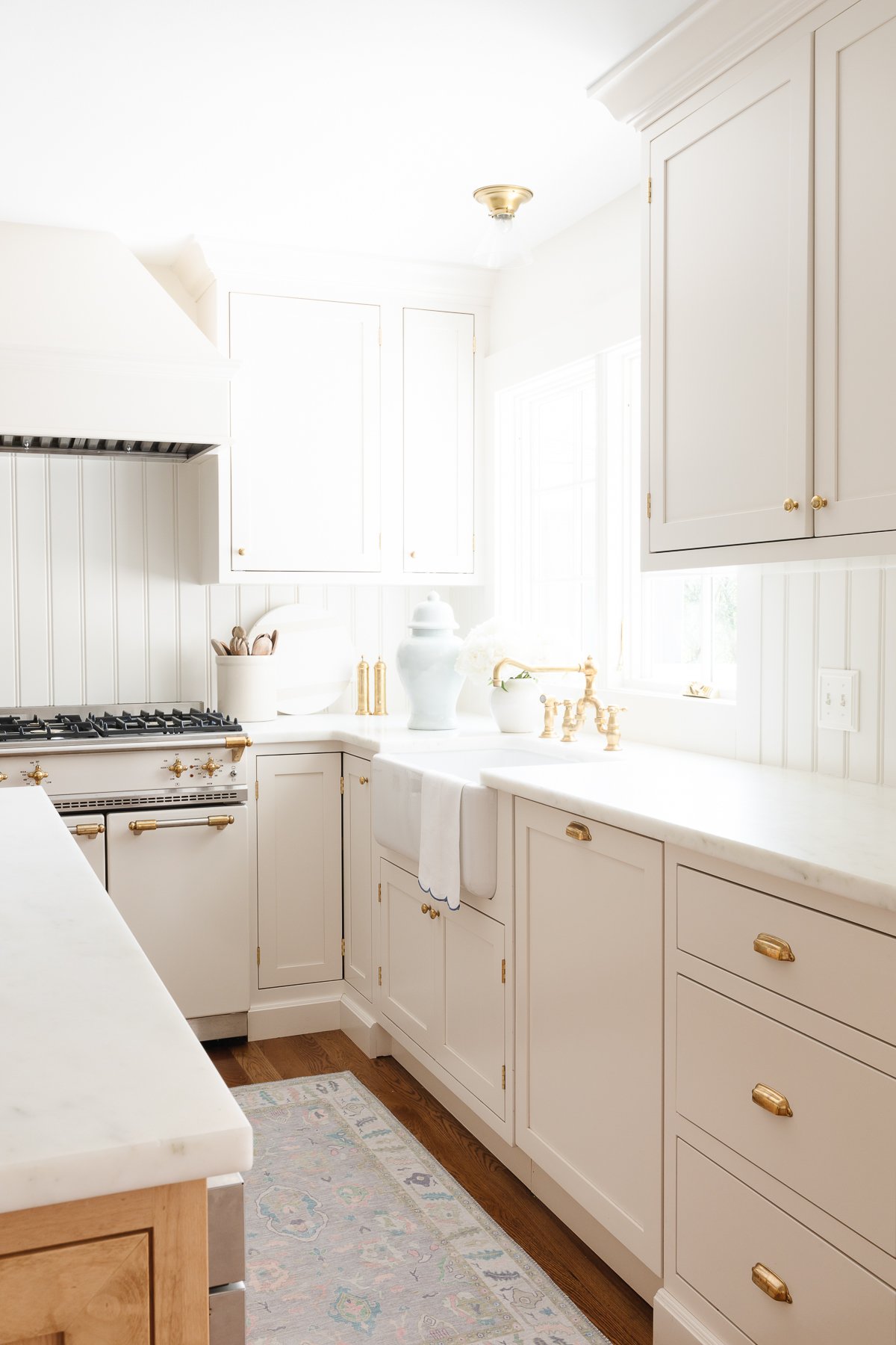 Cream kitchen cabinet with brass knobs in a traditional kitchen.