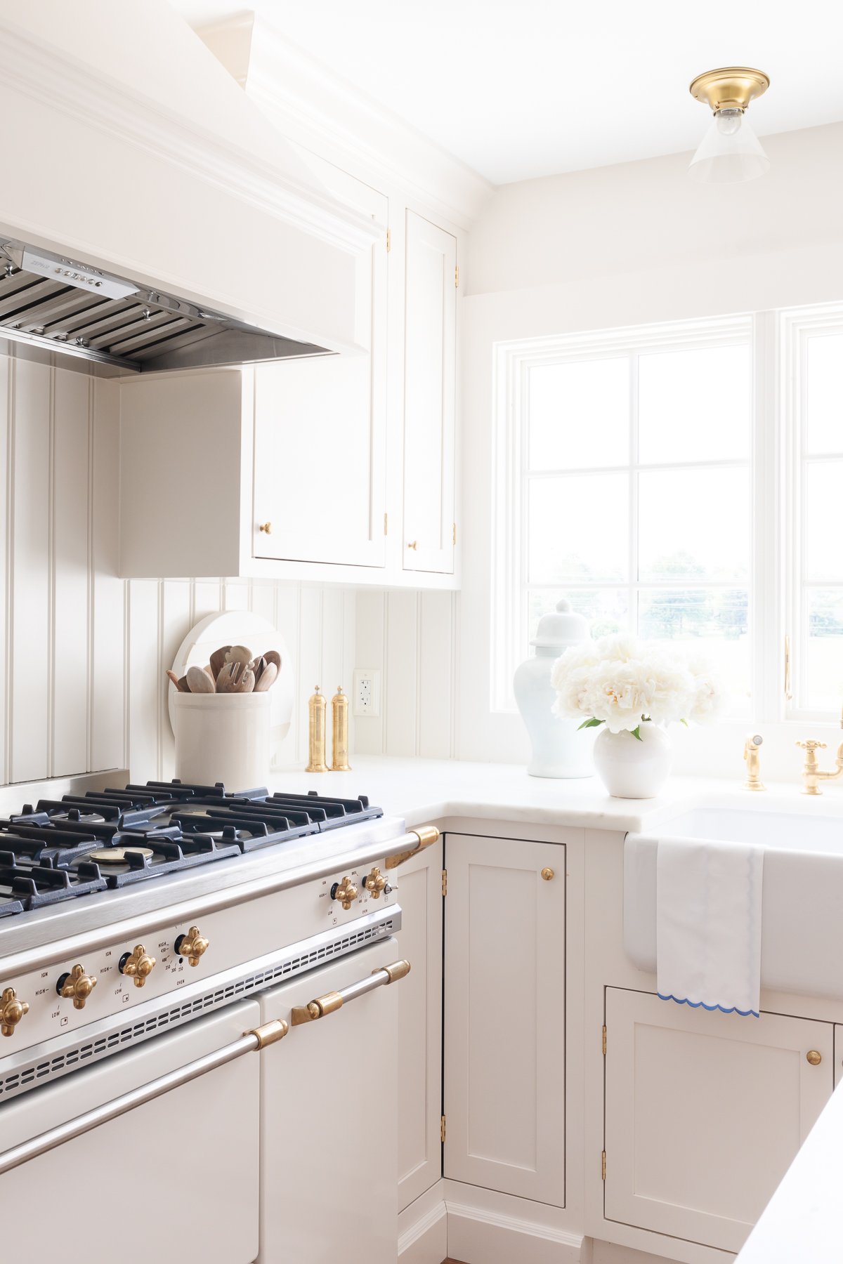 Cream kitchen cabinet with brass knobs in a traditional kitchen.