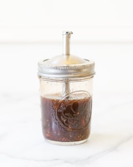 A mason jar salad dressing dispenser full of homemade balsamic vinaigrette.