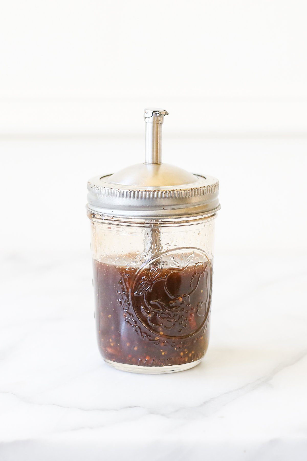 A mason jar salad dressing dispenser full of homemade balsamic vinaigrette.