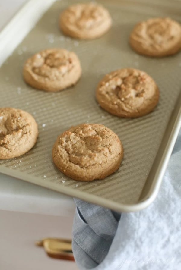 Brown sugar cookies on a gold baking sheet after coming out of the oven.