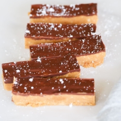 No bake Speculoos cookie butter bars on a marble countertop, dusted with powdered sugar.