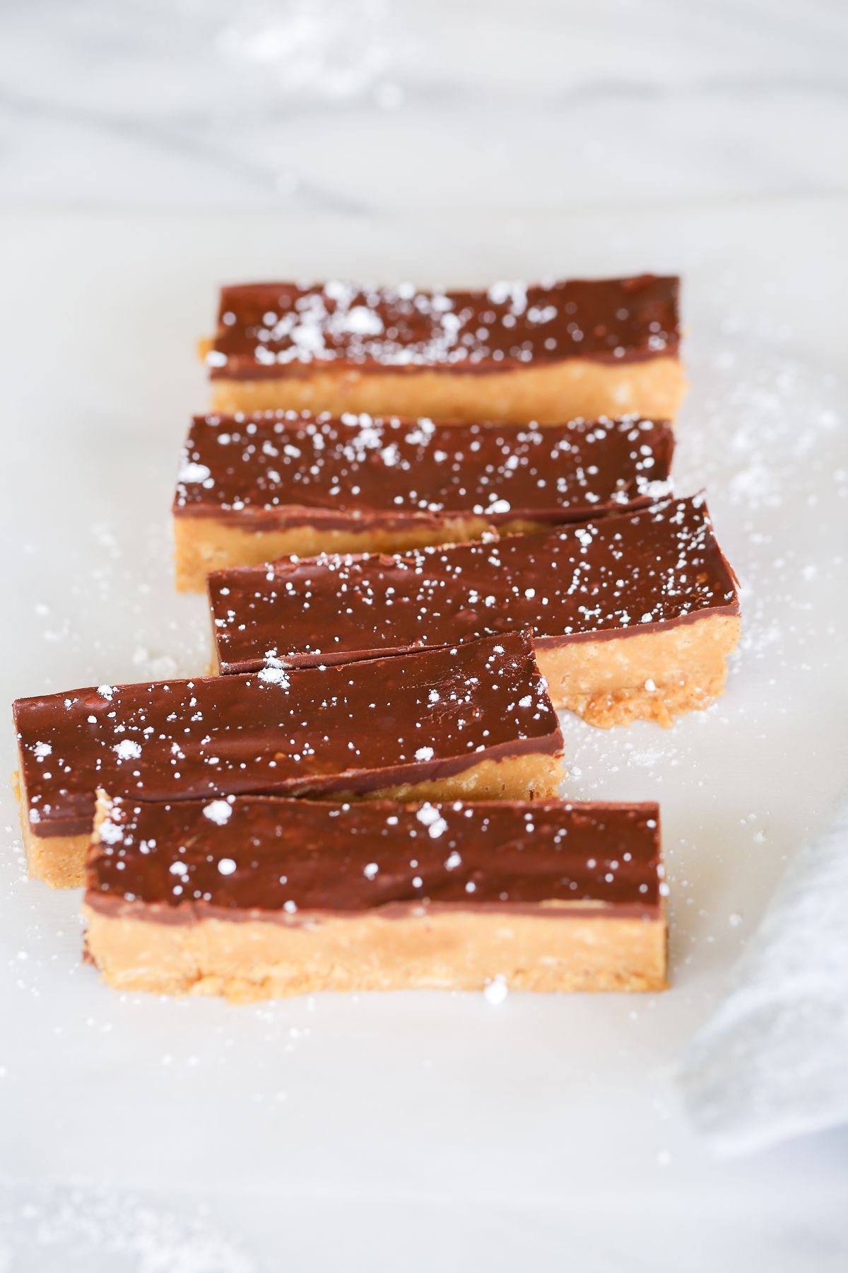 No bake Speculoos cookie butter bars on a marble countertop, dusted with powdered sugar.