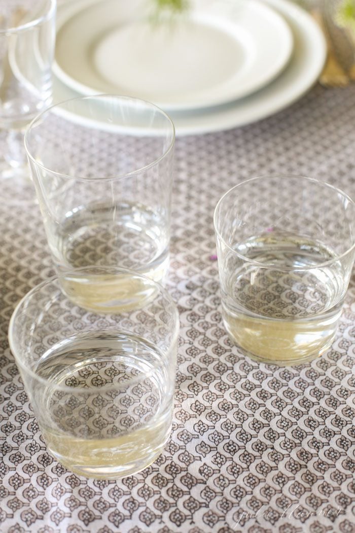 use glasses as impromptu vases at varying heights to create a beautiful centerpiece that fills a long table