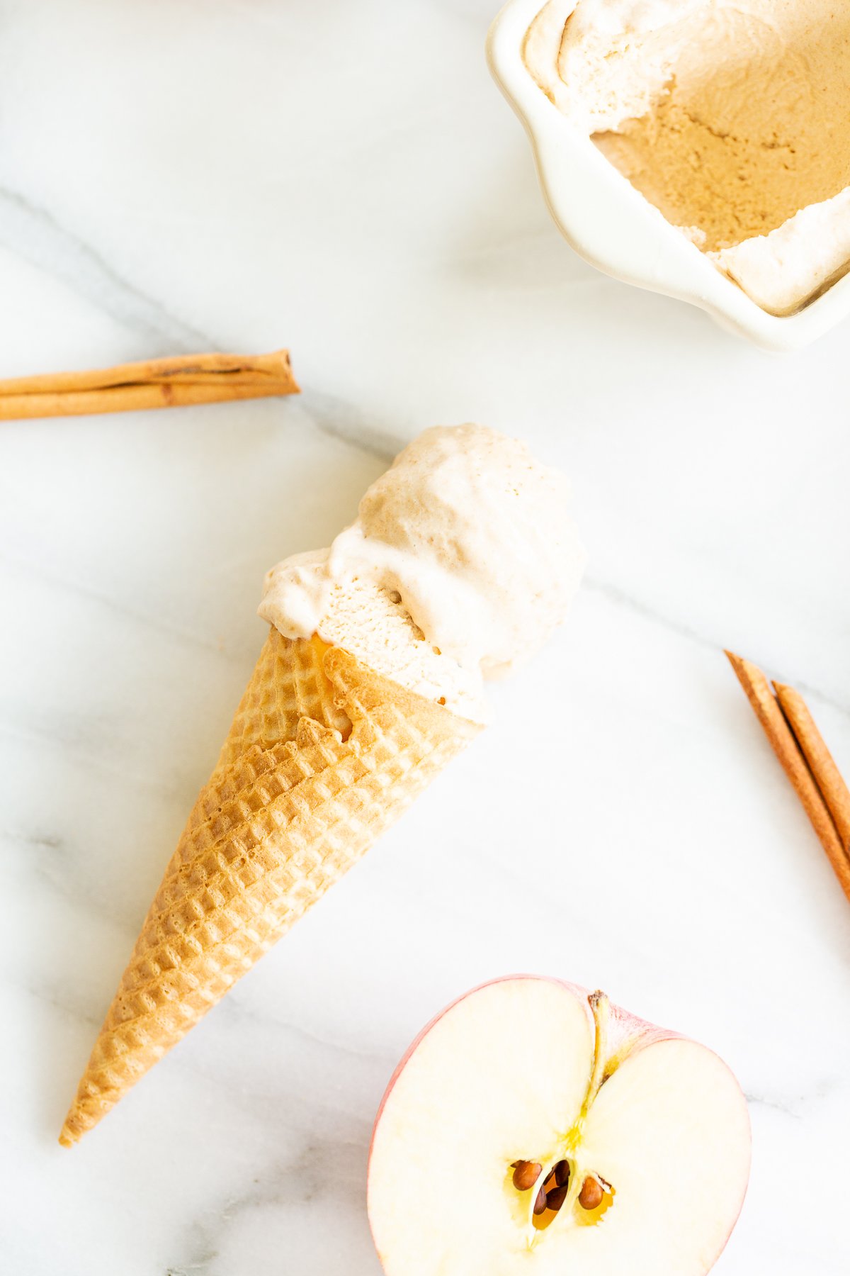 A bowl of apple-flavored ice cream with cinnamon sticks.