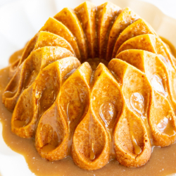 A brown sugar caramel pound cake on a white platter, baked in a bundt pan and topped with caramel sauce.