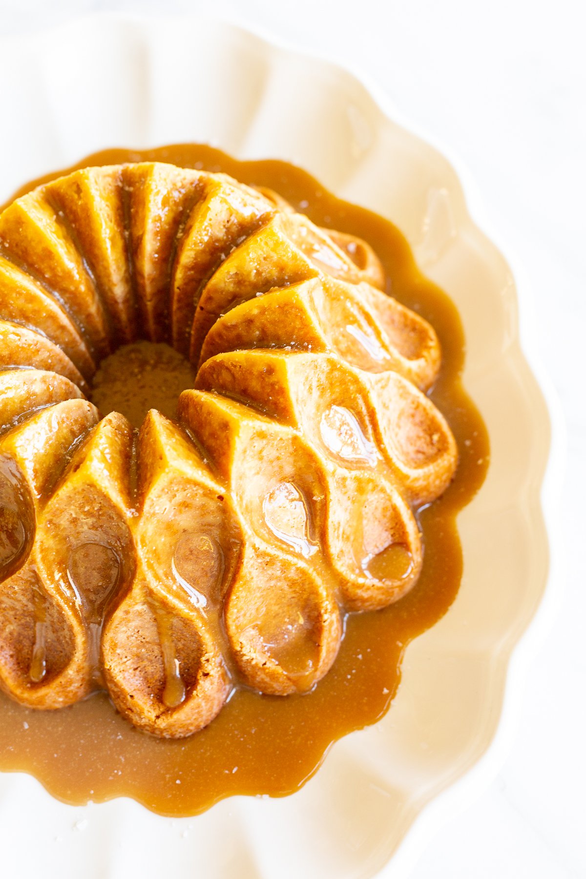 A brown sugar caramel pound cake on a white platter, baked in a bundt pan and topped with caramel sauce.