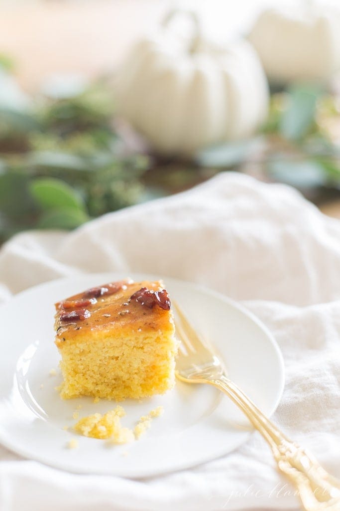 A piece of homemade cornbread on a white plate with a fork