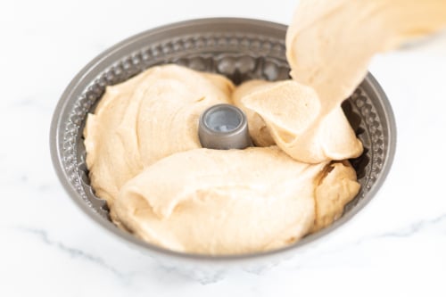 Peanut butter icing being poured onto a cinnamon pound cake.