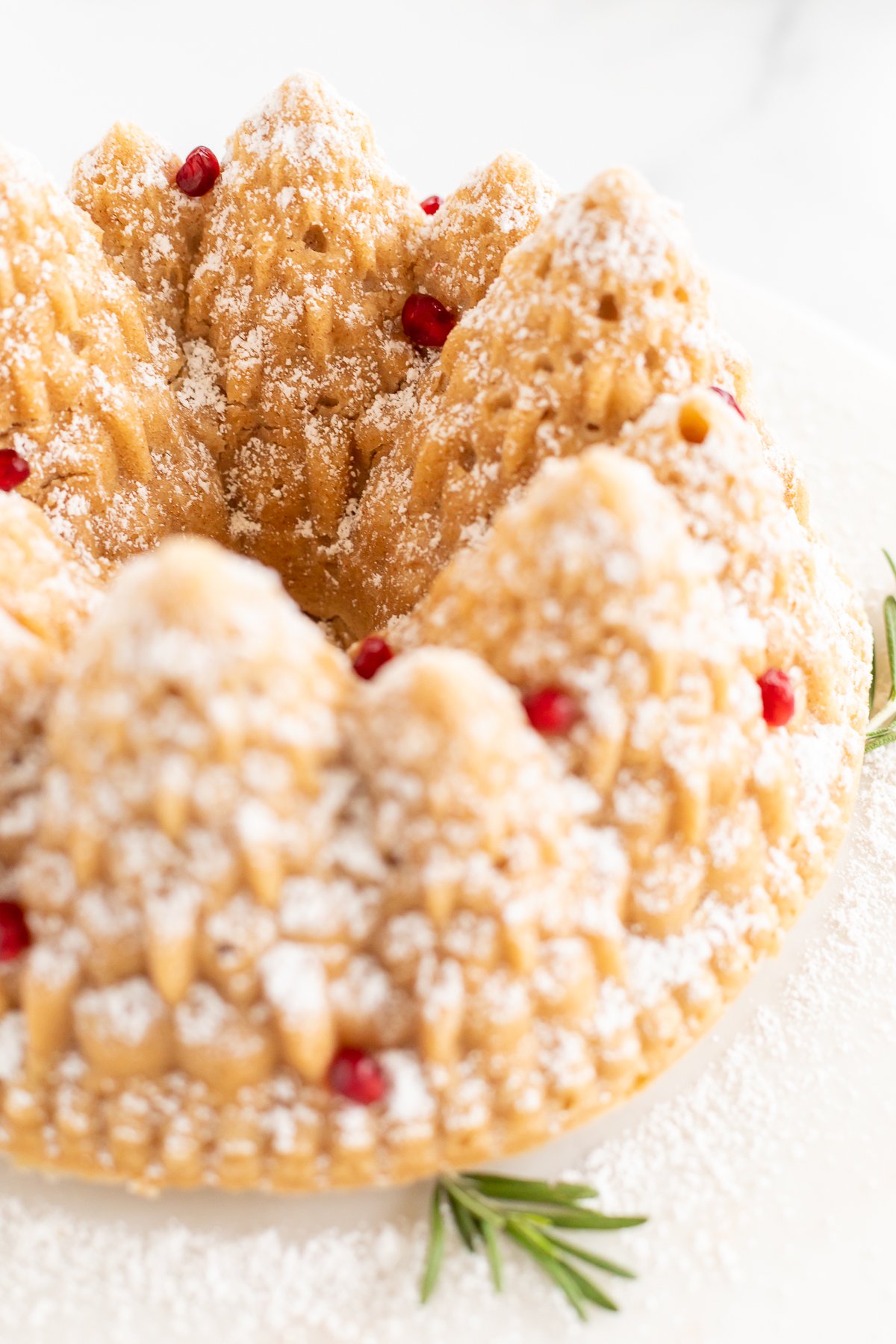 A cinnamon pound cake topped with powdered sugar and rosemary.