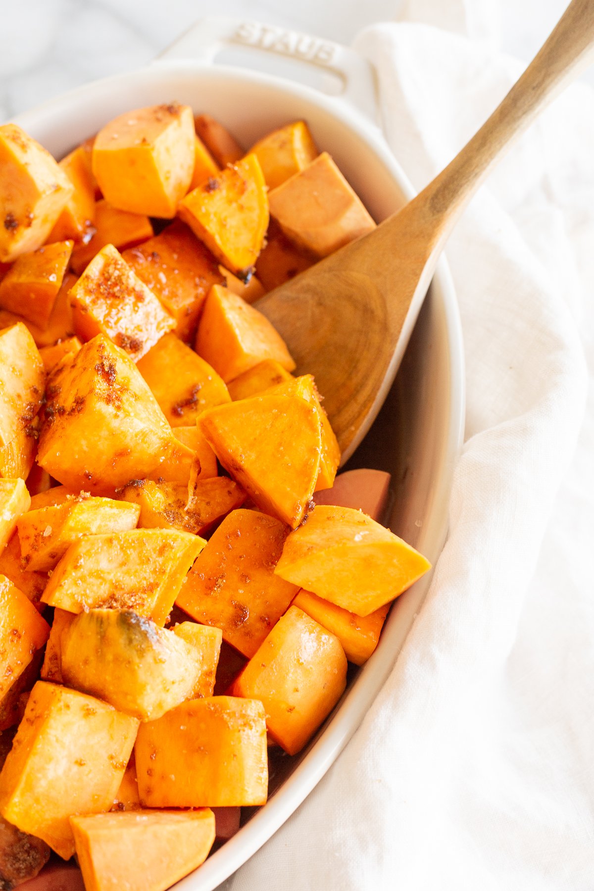 A white oval baking dish filled with roasted sweet potatoes.