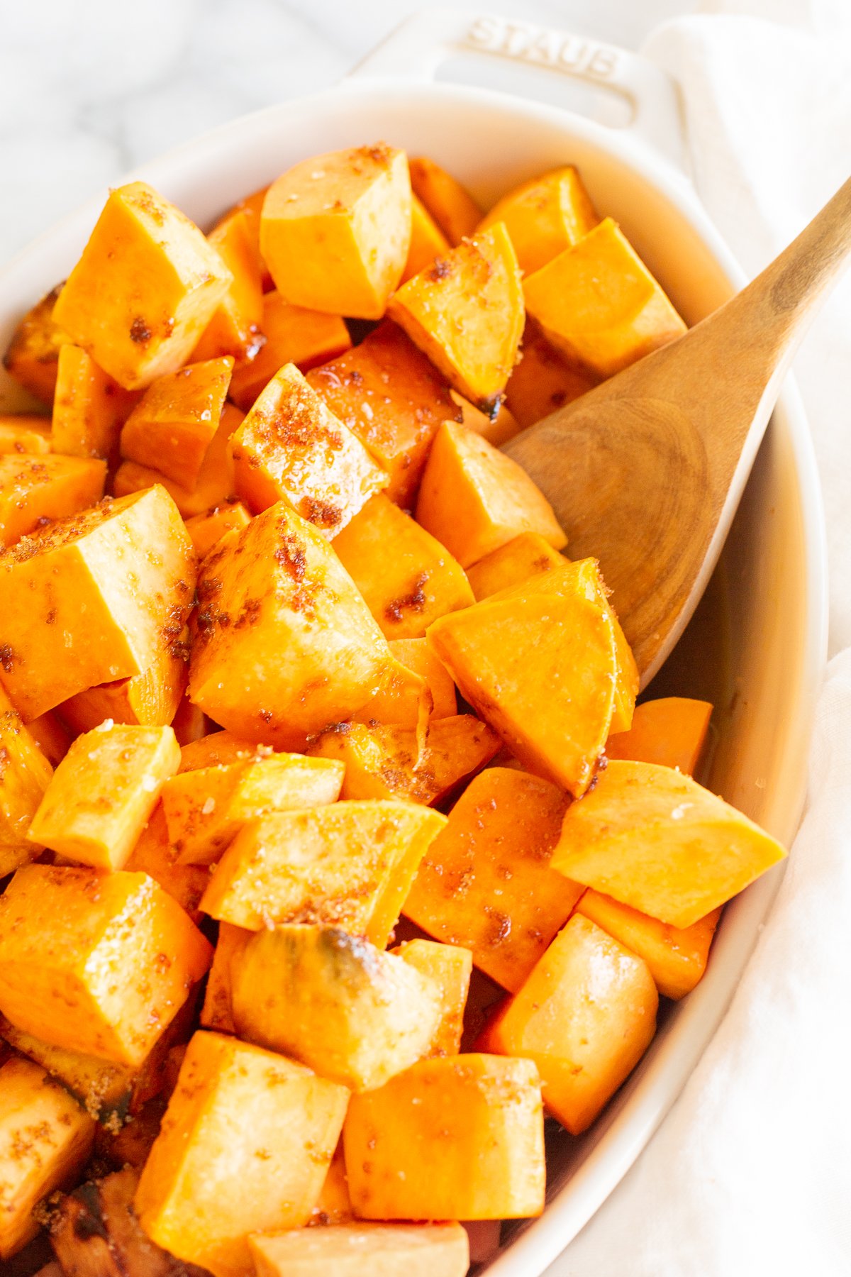 A white oval baking dish filled with roasted sweet potatoes.