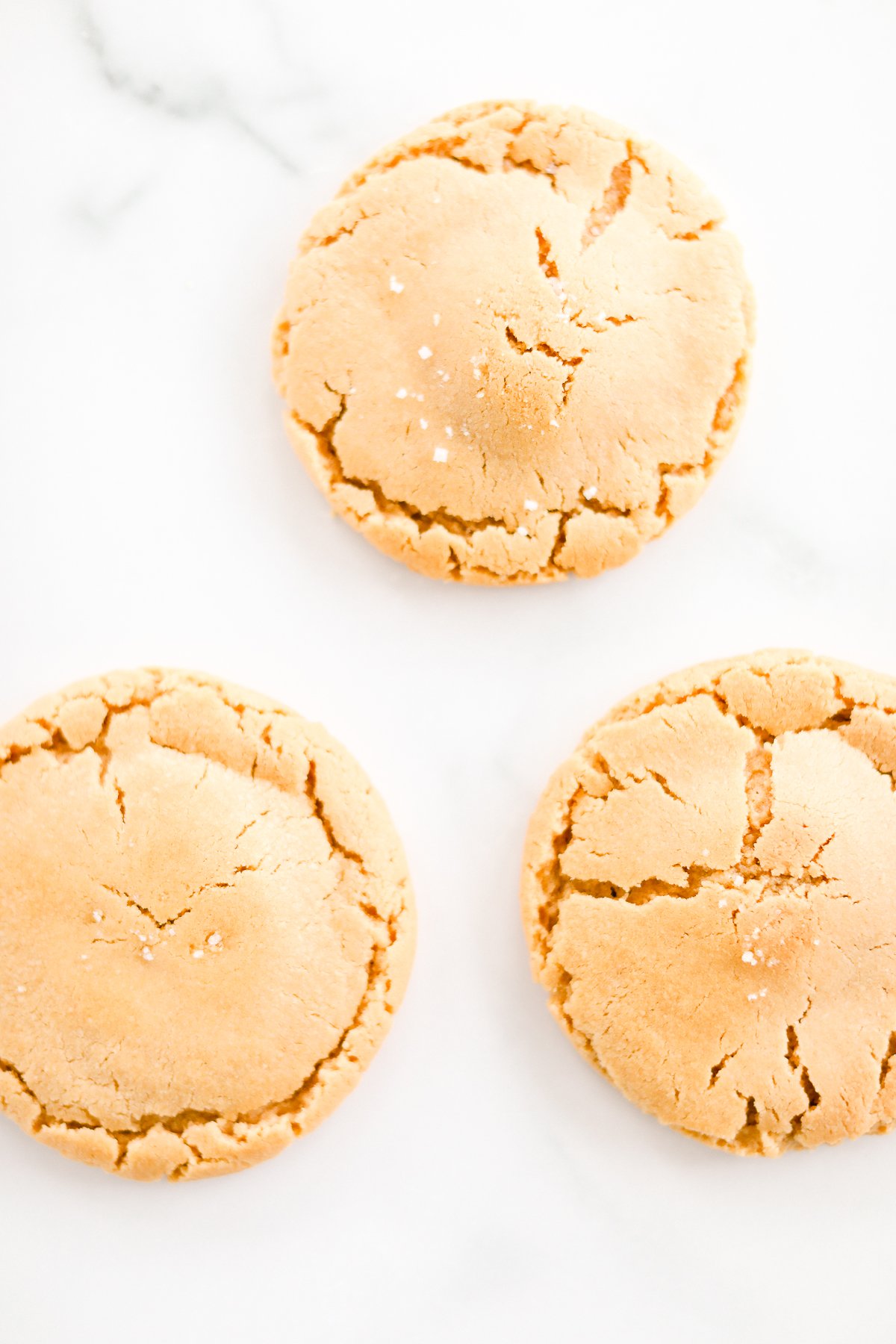 Three stuffed peanut butter cookies on a marble table.