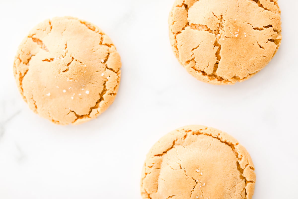 Three stuffed peanut butter cookies on a marble surface.