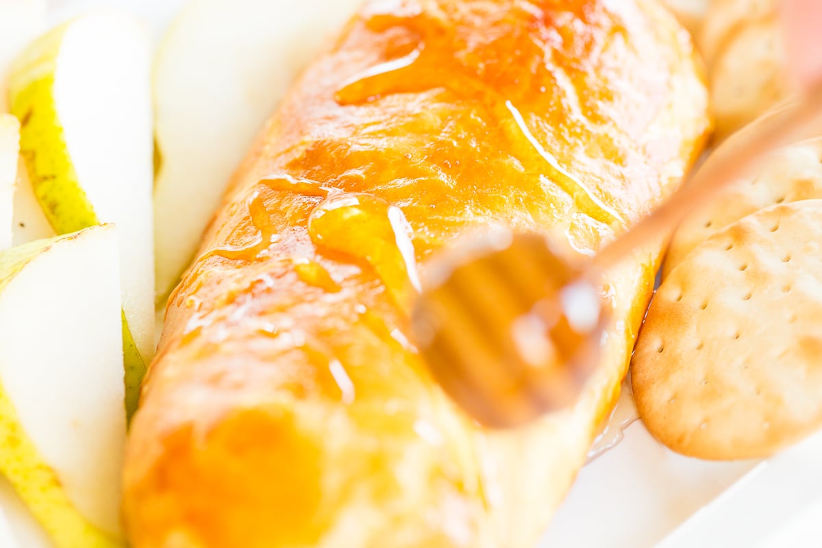 Baked goat cheese topped with honey with sliced pears and crackers for serving.