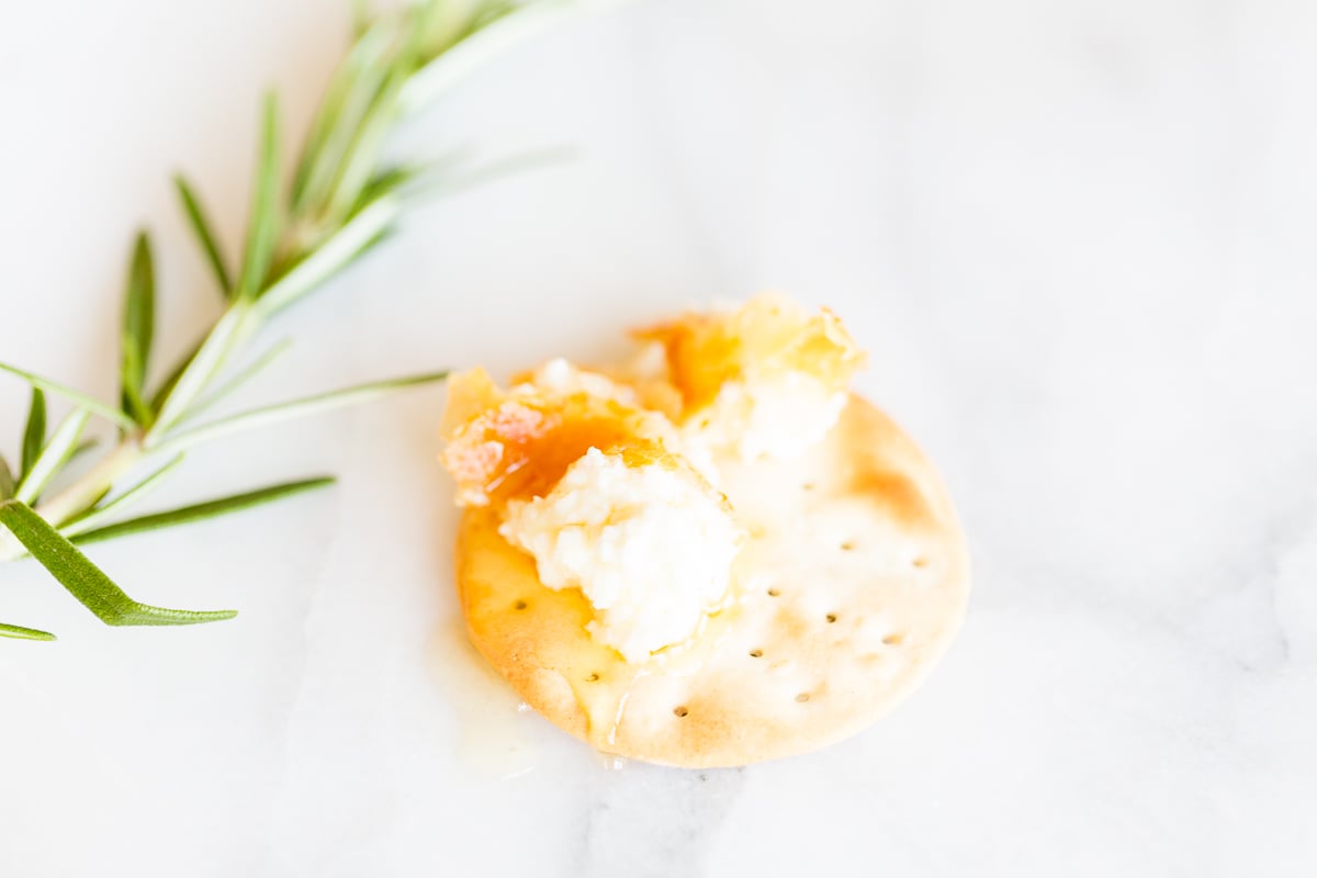 Goat cheese on a cracker with a stem of rosemary to the side