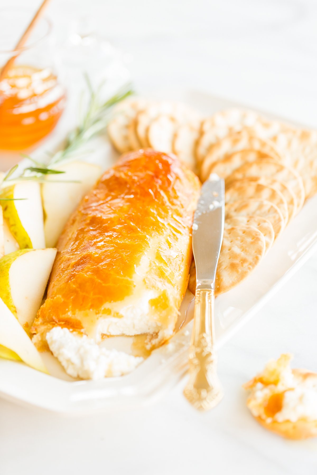 Baked goat cheese topped with honey with sliced pears and crackers for serving. 