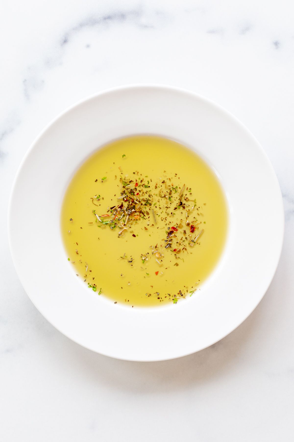 A white plate topped with bread dipping seasoning and olive oil.