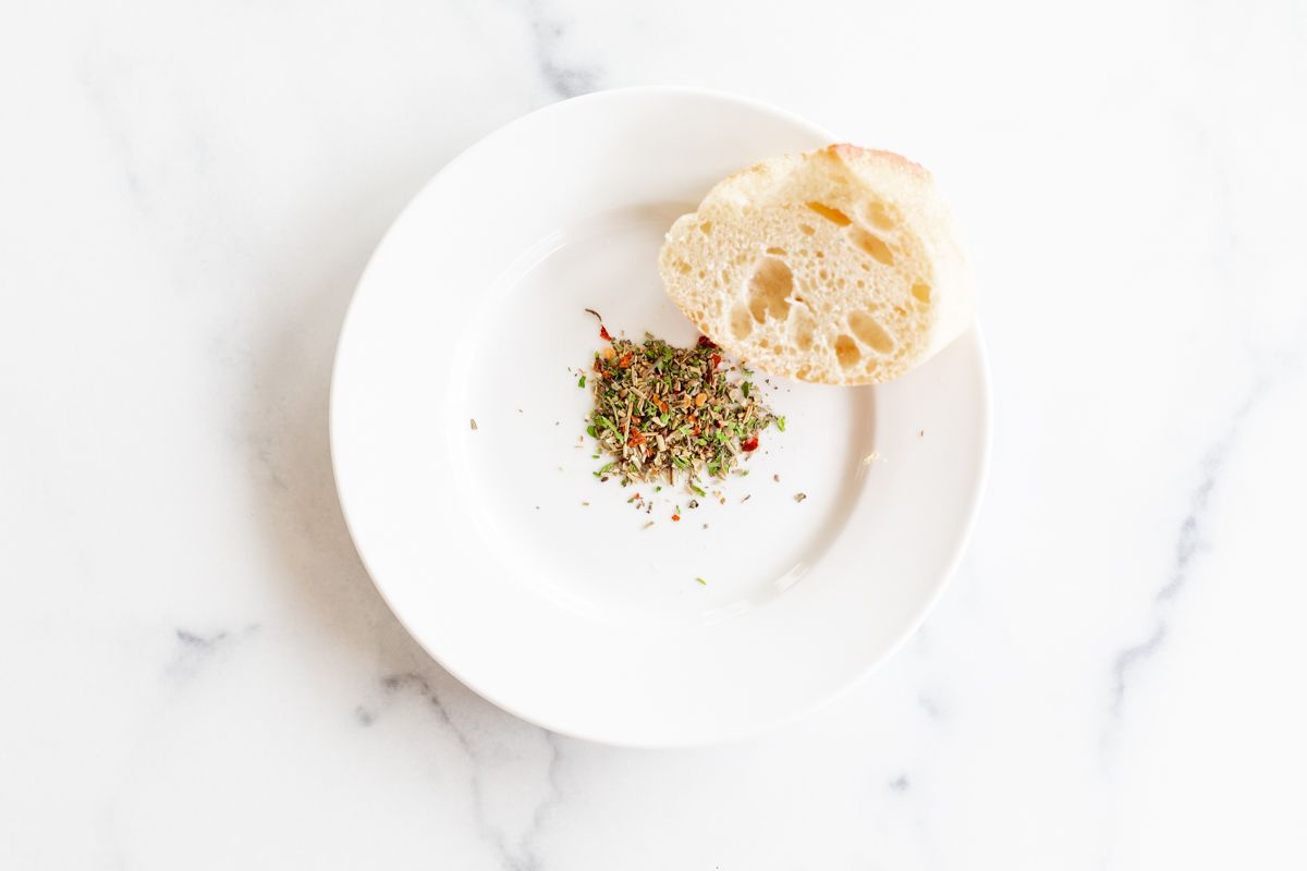 A white plate topped with bread dipping seasoning.