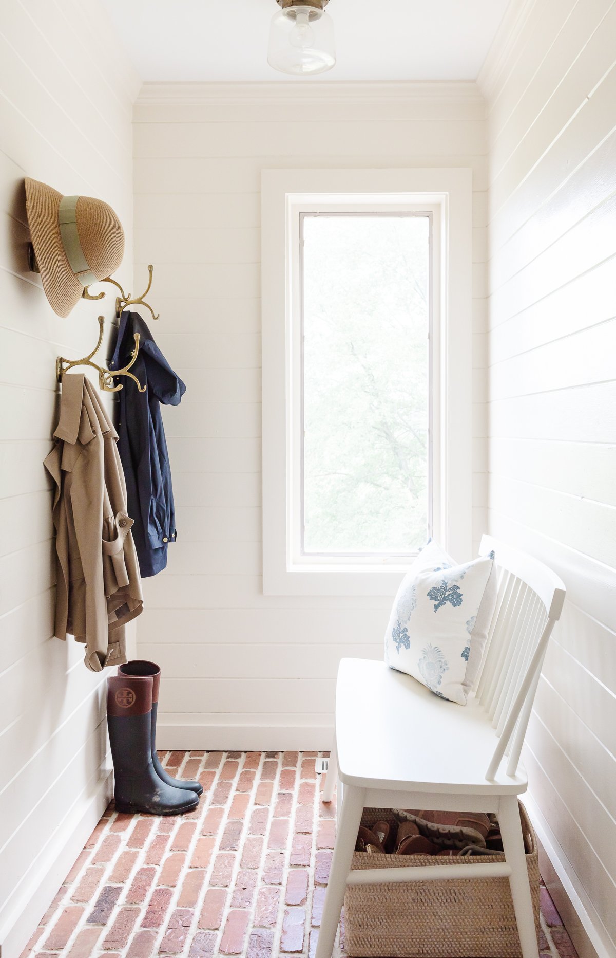 A mudroom with brick flooors, painted in Benjamin Moore Navajo White.