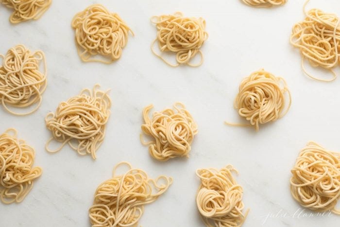 small swirls of spaghetti style egg noodles on a marble countertop