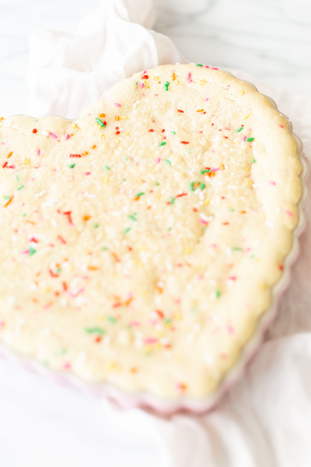 A funfetti cookie cake baked into a heart shaped pan.
