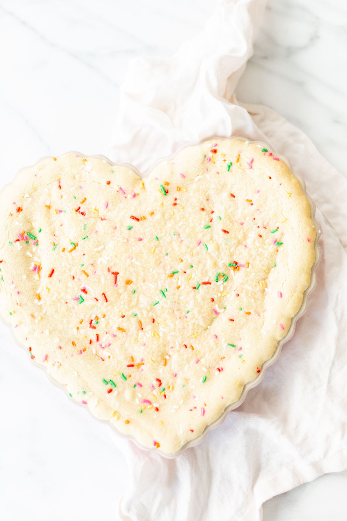 A funfetti cookie cake baked into a heart shaped pan.