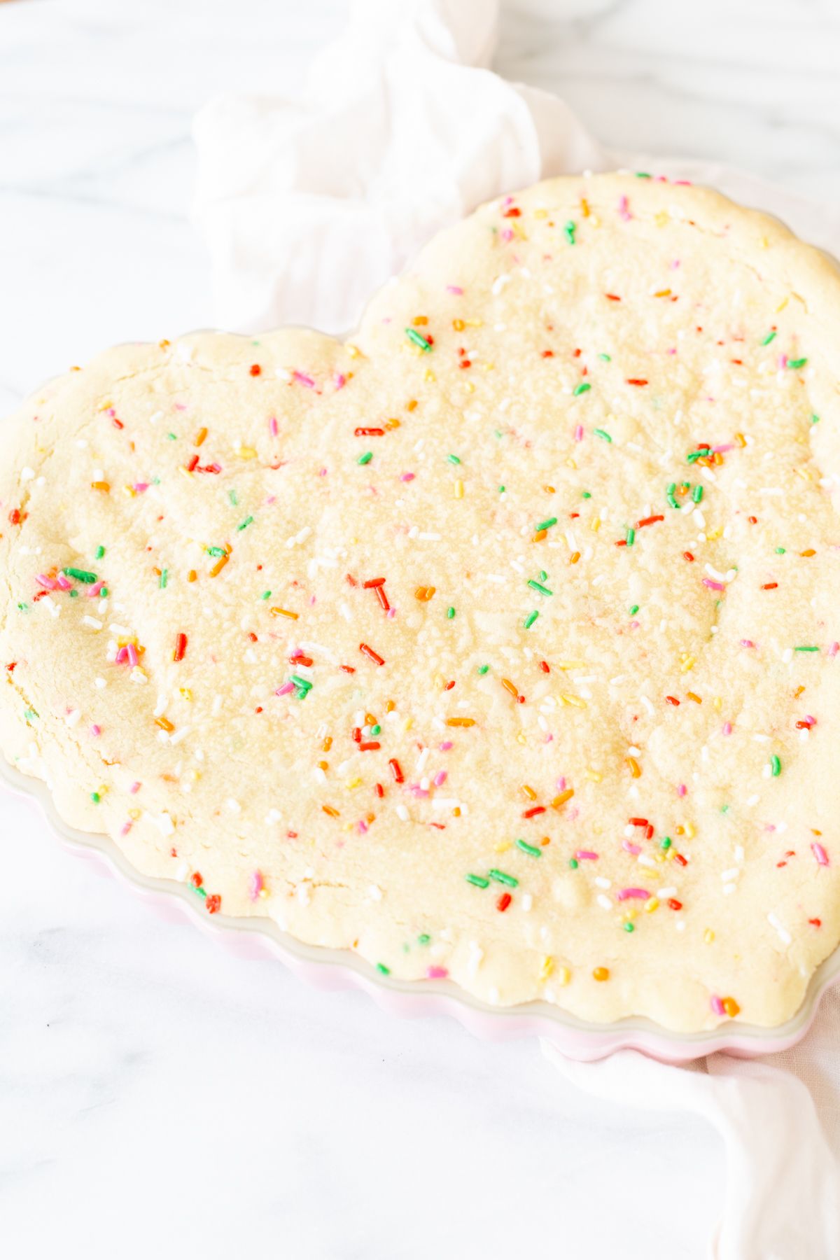 A funfetti cookie cake baked into a heart shaped pan.
