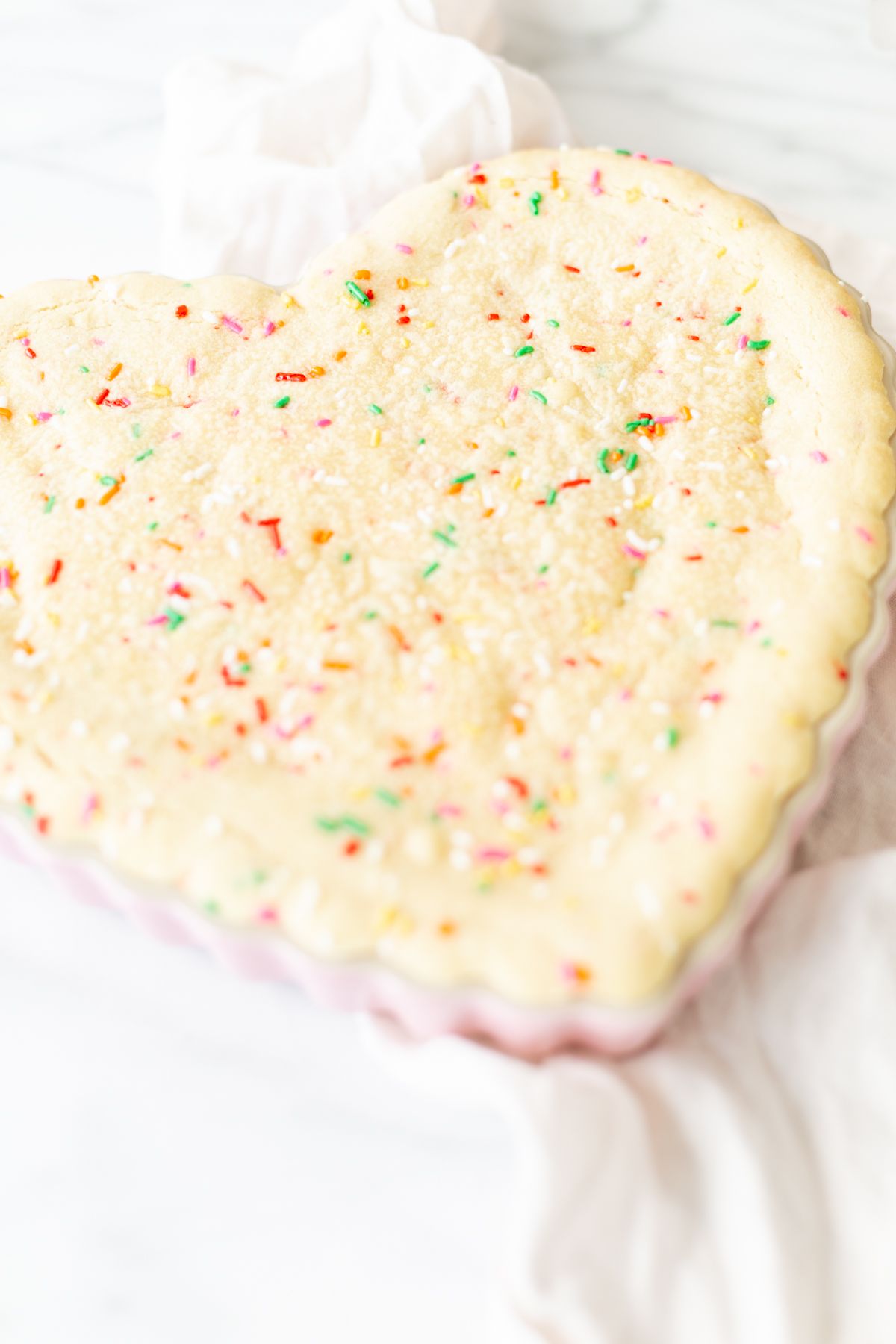 A funfetti cookie cake baked into a heart shaped pan.