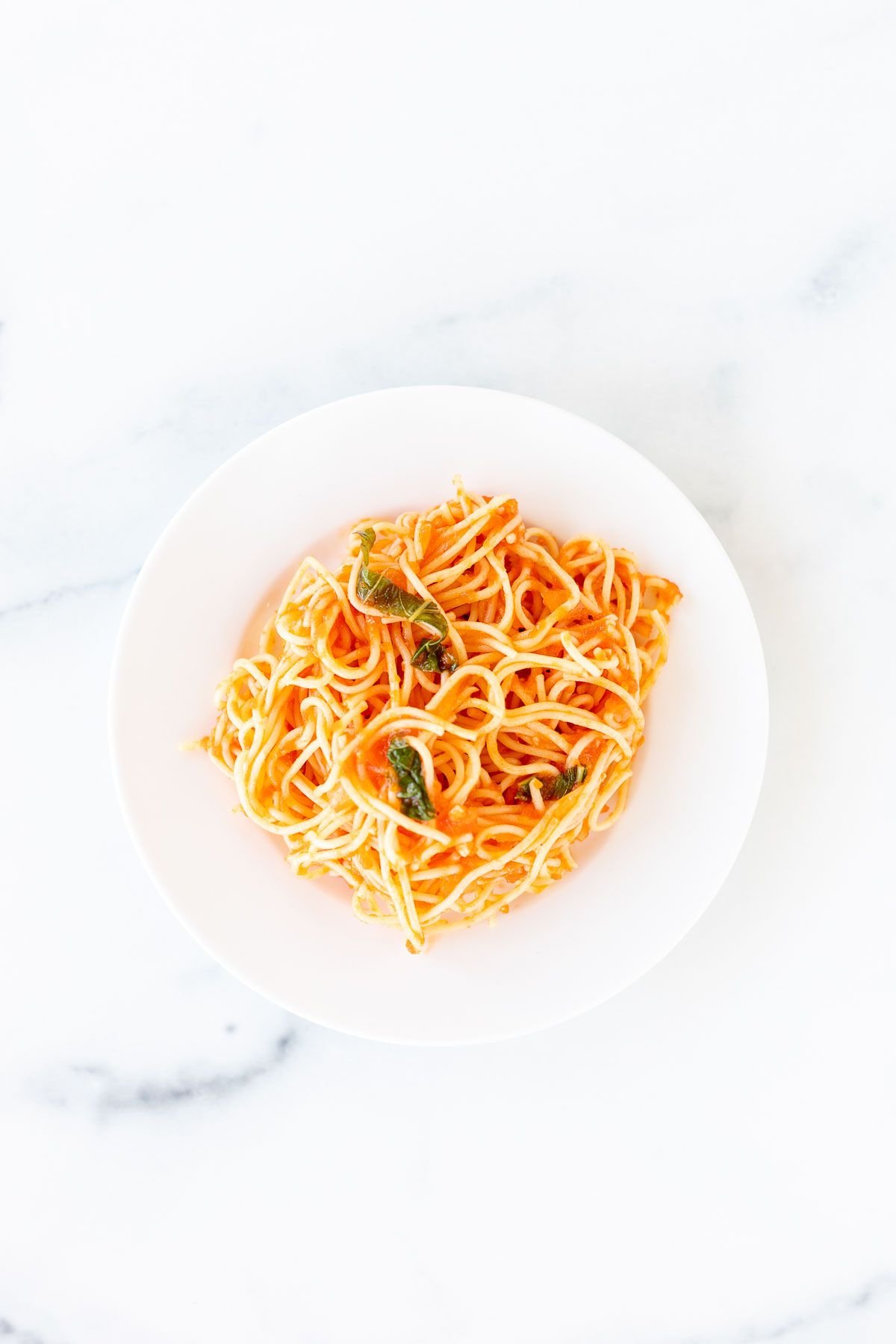 A white plate filled with pasta in a pomodoro sauce