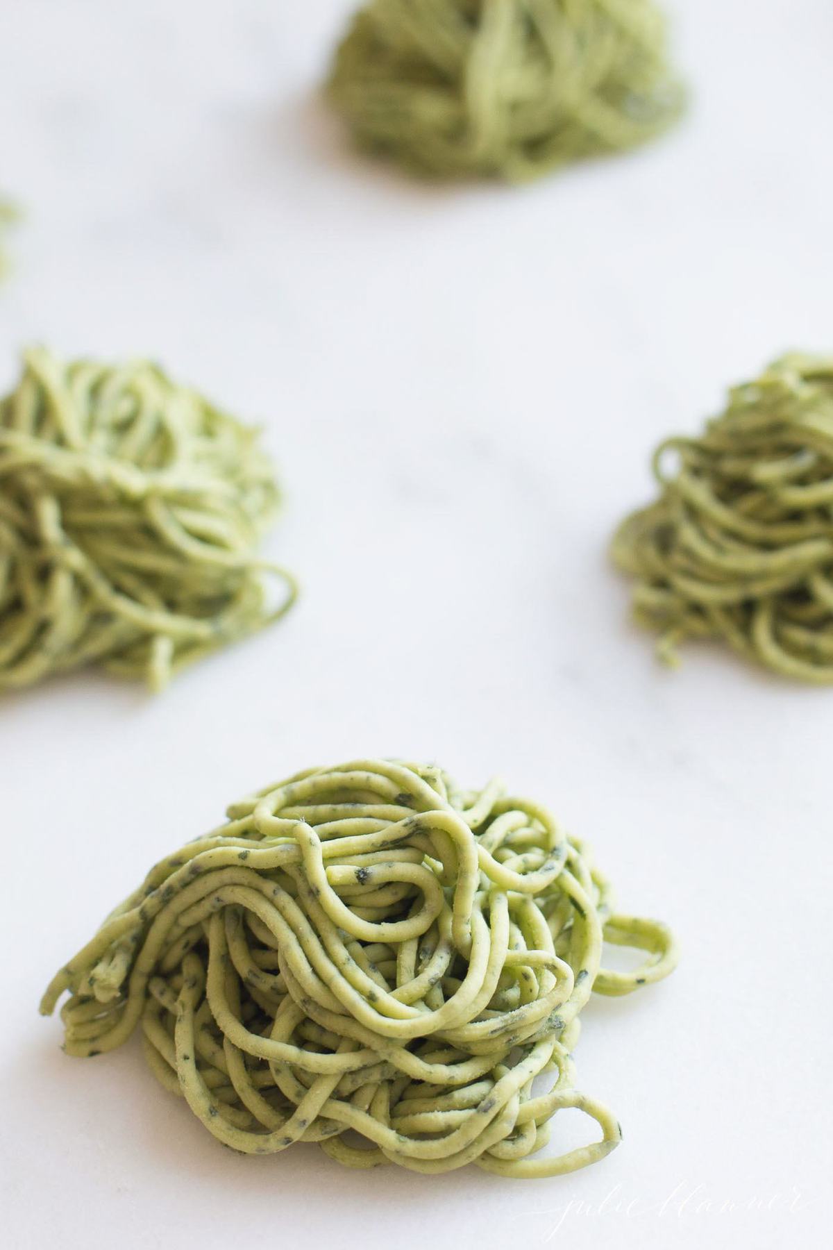 Uncooked arugula pasta in small piles