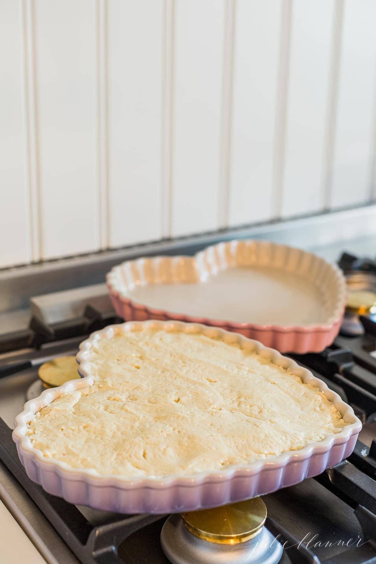Two heart shaped pans with a peanut butter cookie cake on a stove top.