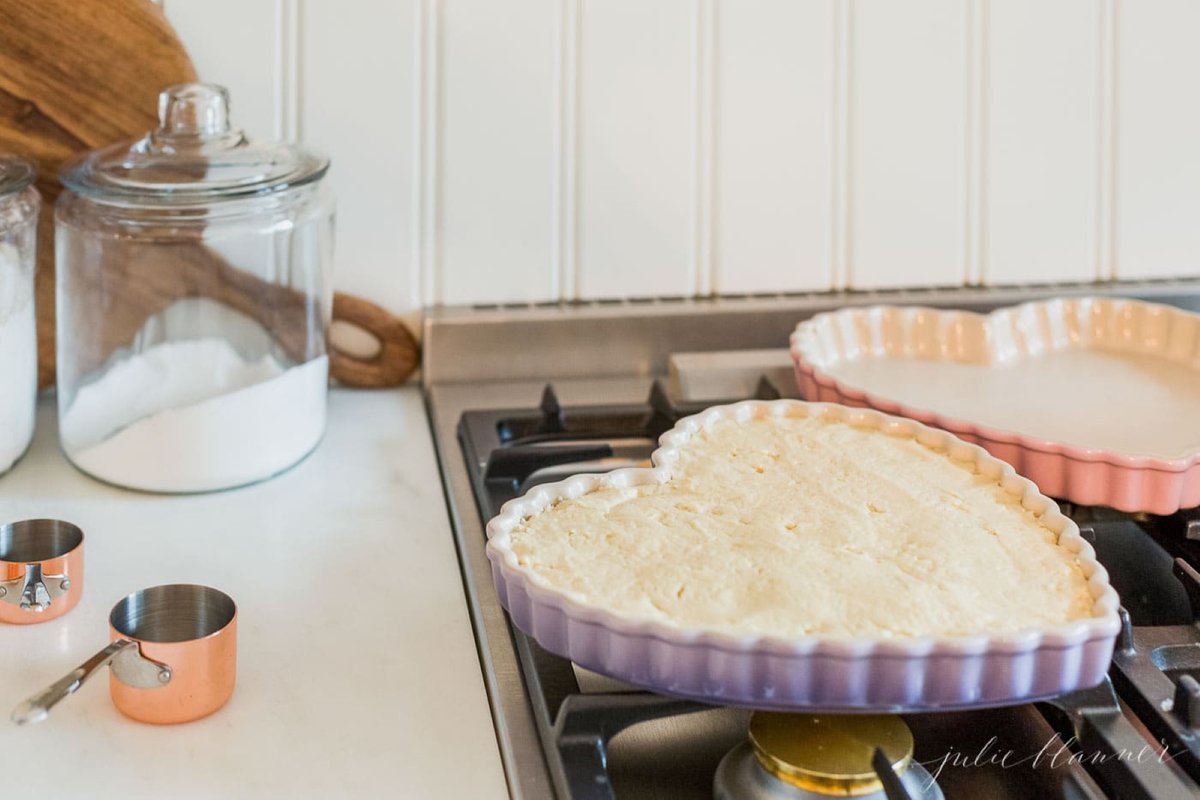 Two heart shaped pans with a peanut butter cookie cake on a stove top.