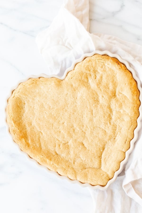 A heart shaped peanut butter cookie cake on a marble countertop.