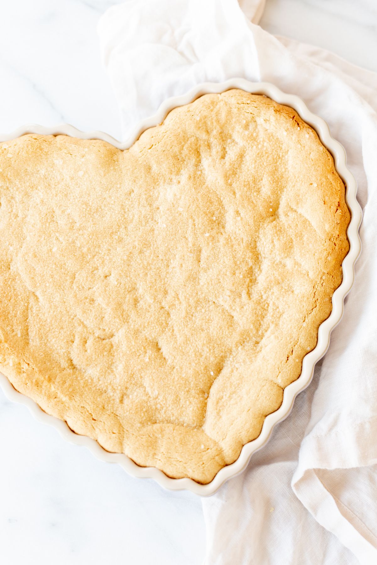 A heart shaped peanut butter cookie cake on a marble countertop.