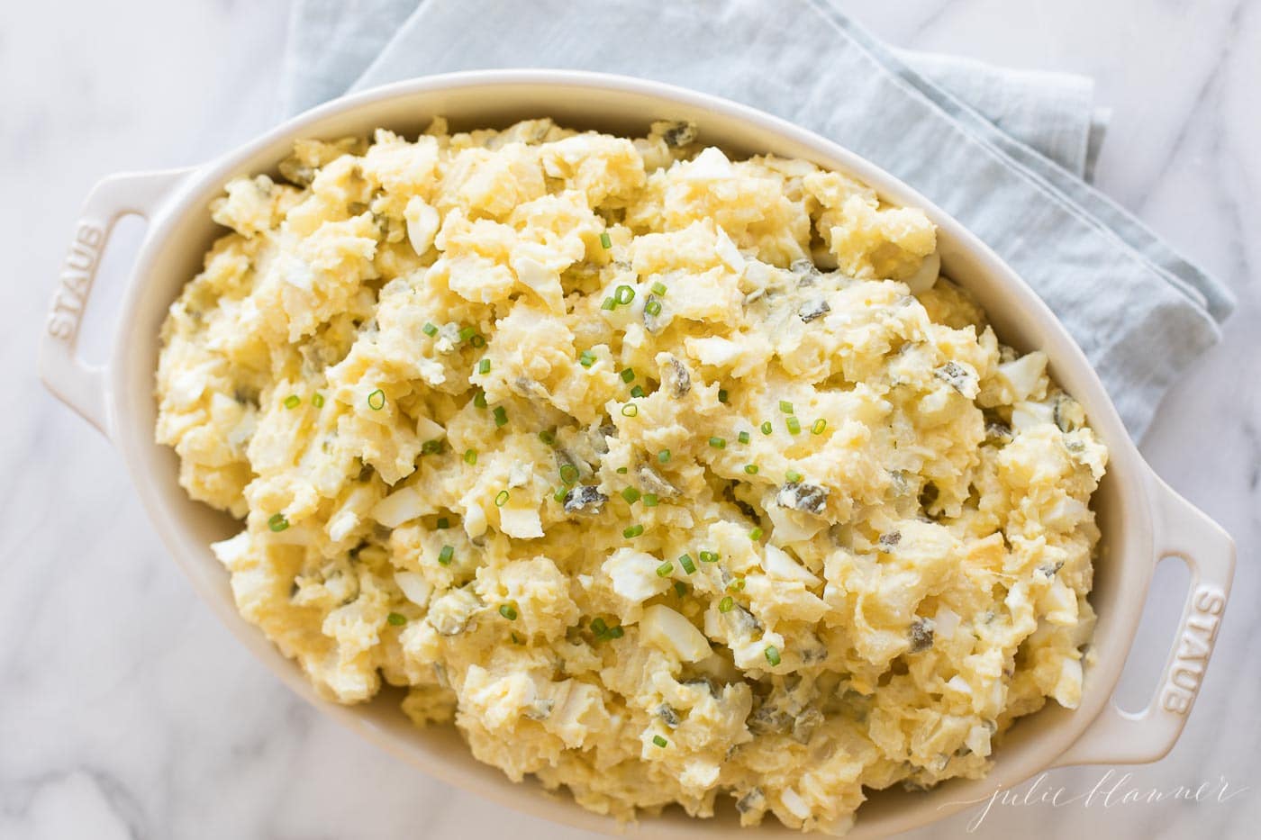 homemade potato salad with eggs in a white casserole dish