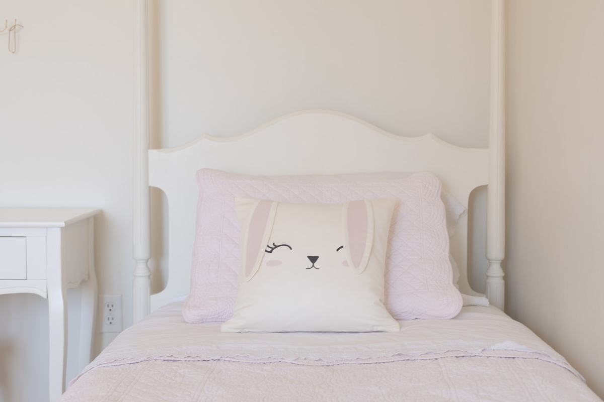 A white girl's bedroom with a cute bunny pillow on the bed for simple easter decorations