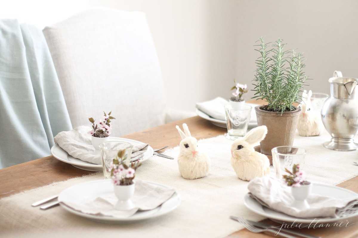 easter decorating ideas on a dining room table filled with egg cups and tiny straw bunnies.