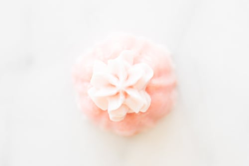 Close-up image of a pink champagne cupcake with delicate icing on top.