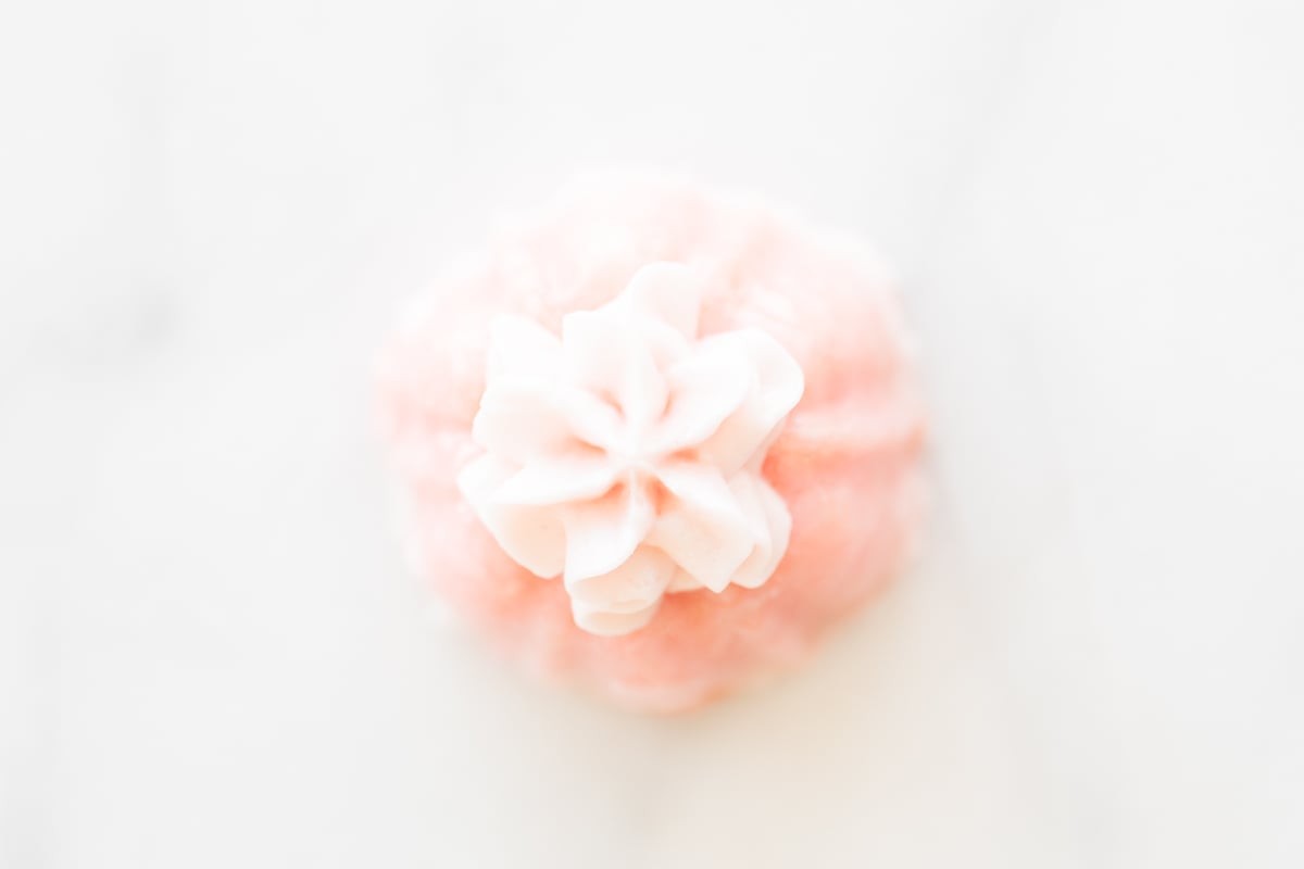 Close-up image of a pink champagne cupcake with delicate icing on top.