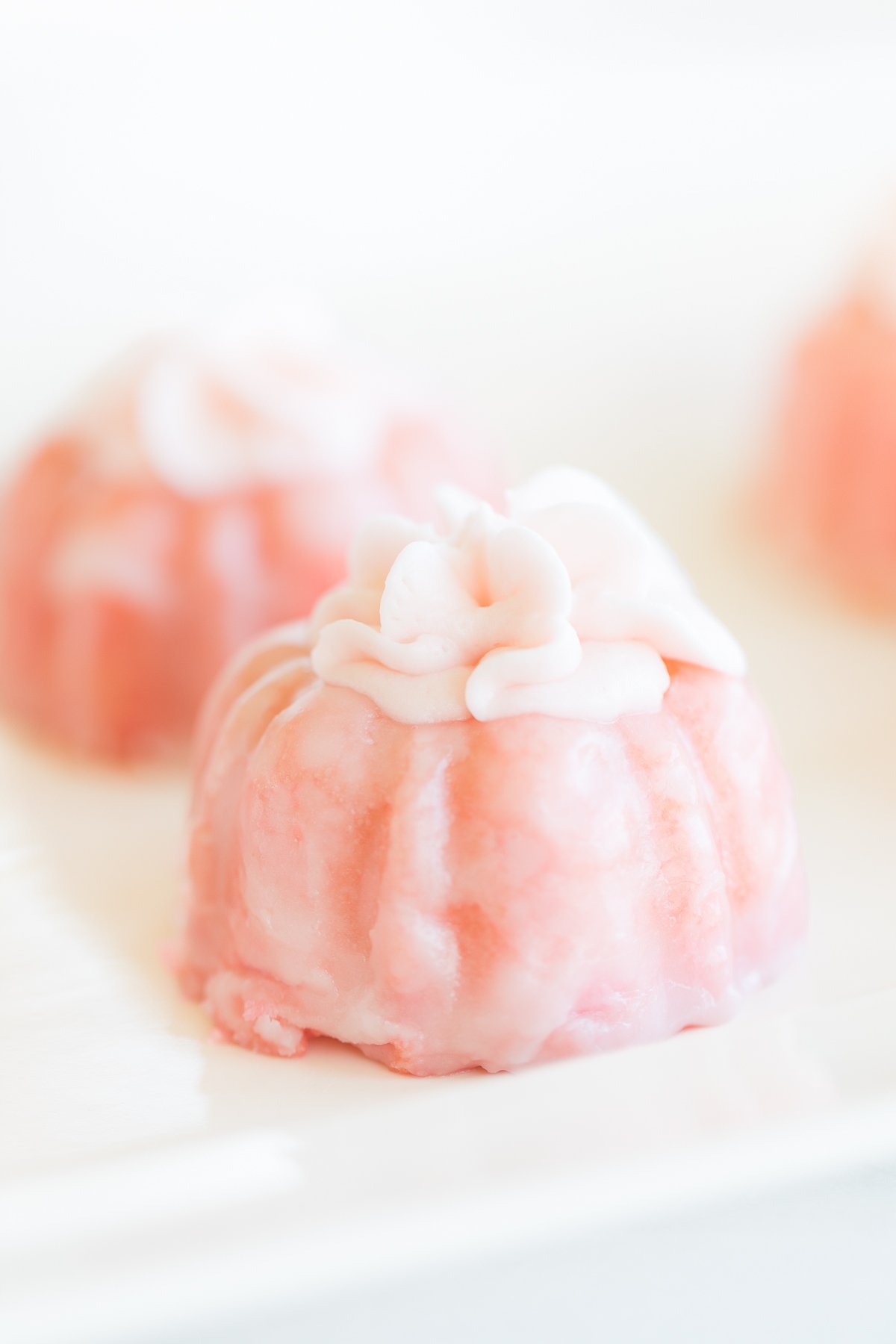 Two pink champagne cupcakes with white floral designs, presented on a light background.