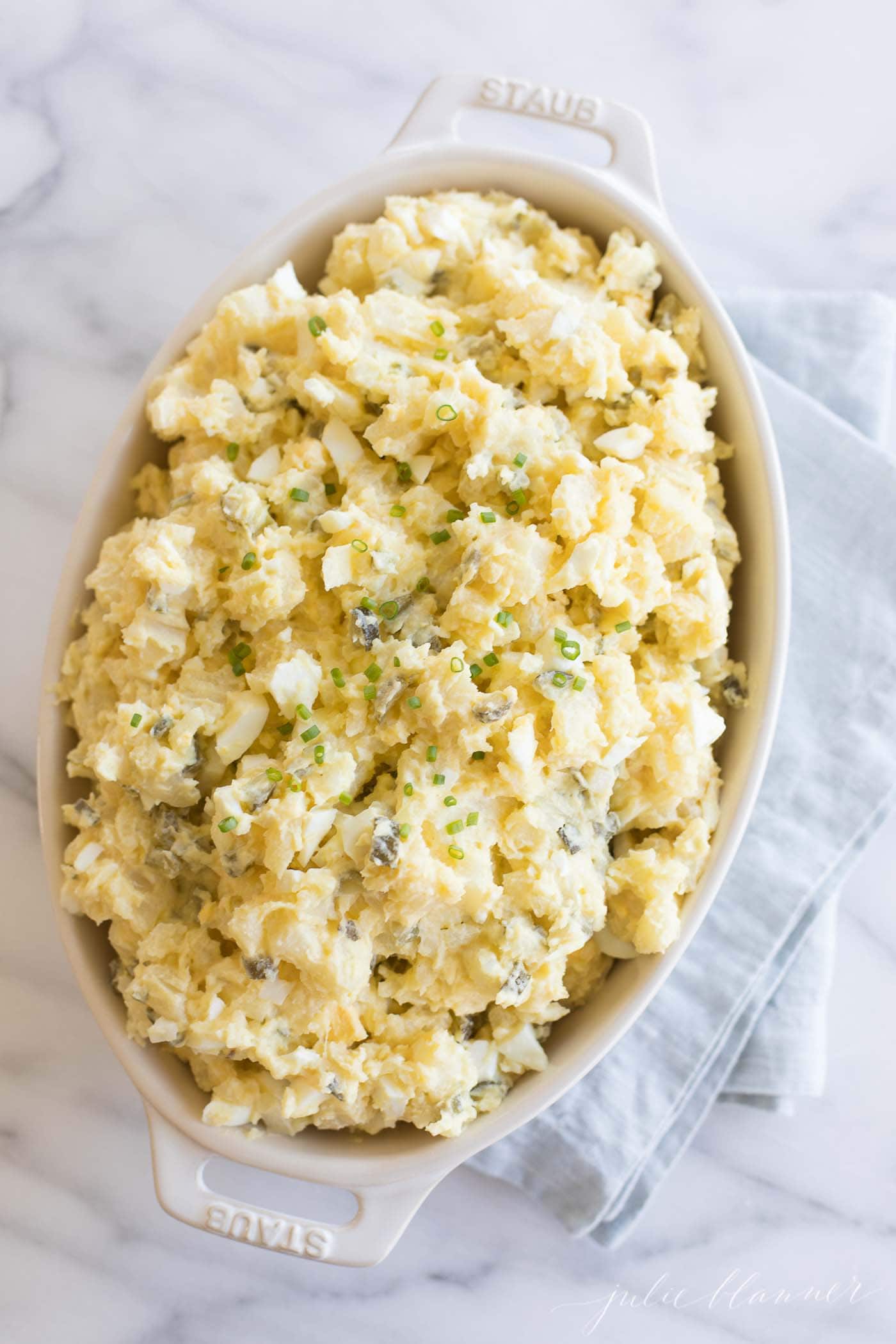 homemade potato salad with eggs in a white casserole dish