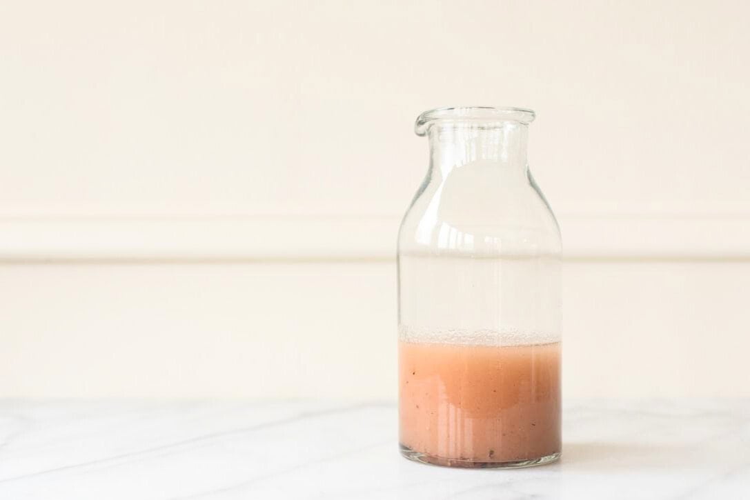 A glass bottle containing a red wine vinaigrette.