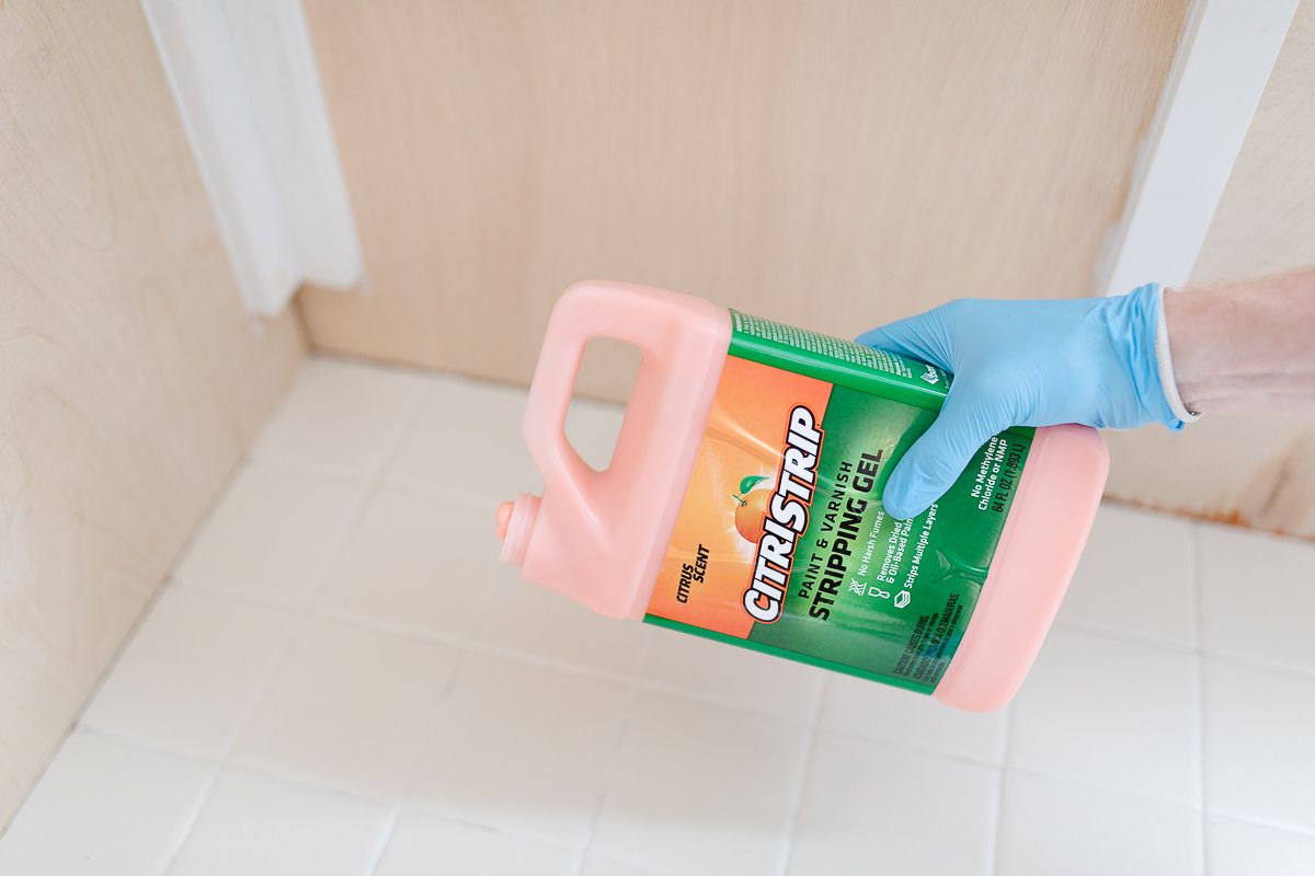 A bottle of Citrus Strip being poured onto old tile for a tile paint tile.