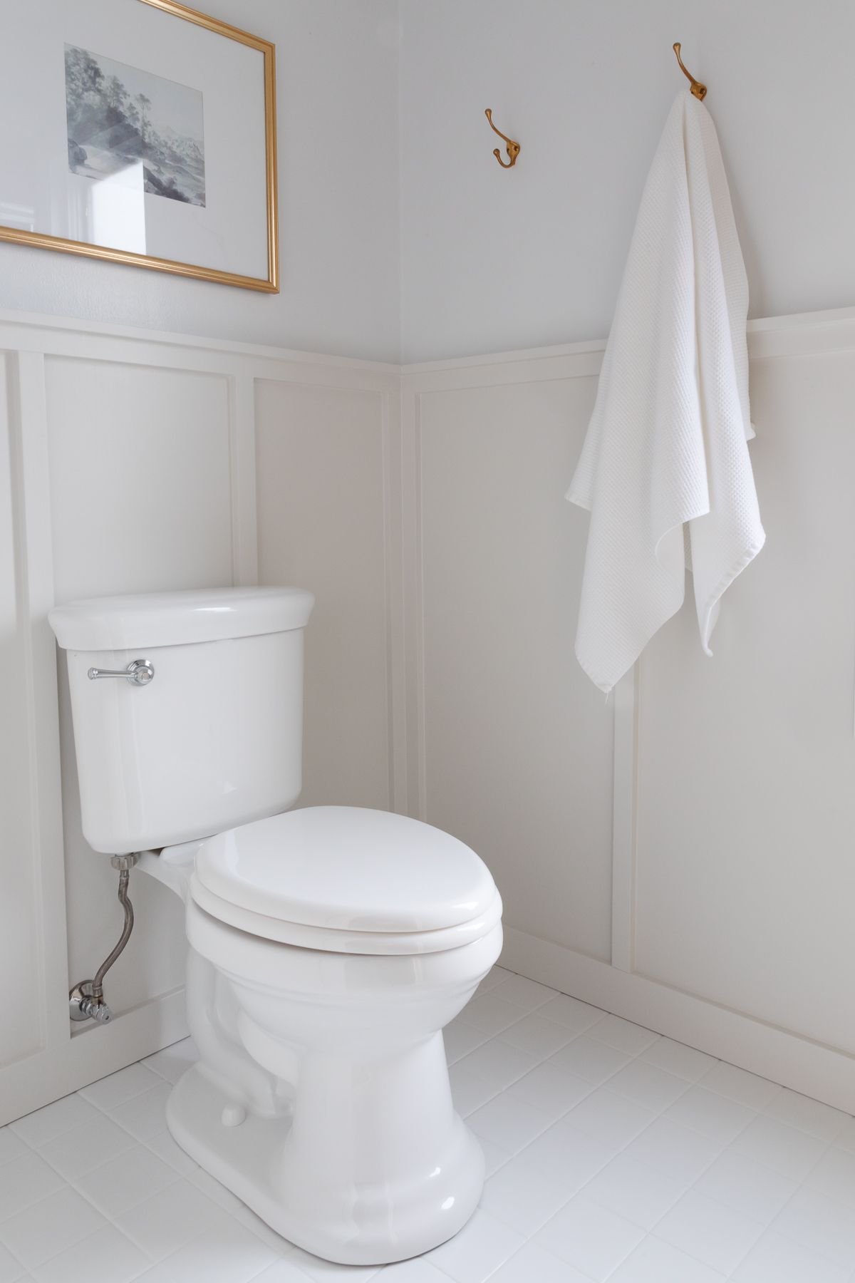 A small bathroom with painted tile and gray board and batten on the walls